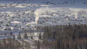 Aerial view of snow-covered village with traditional cabins and smoking chimneys in winter landscape, surrounded by forests and rolling hills - Powered by Shutterstock - Get 15% off with code: PIKWIZARD15