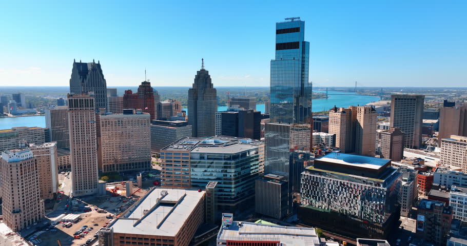 Varied multi-storied buildings and high-rises in Detroit, Michigan, USA. Blue waterscape of the Detroit River at backdrop. Aerial view.