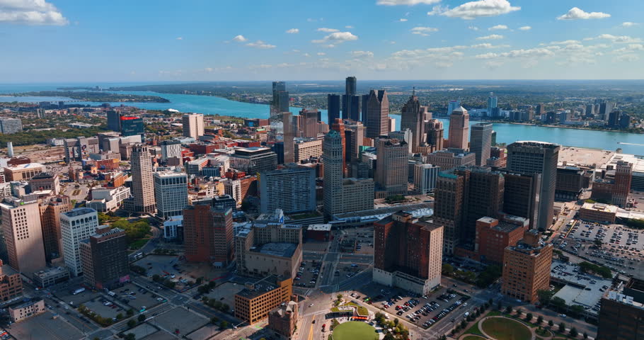 Multiple cars parked on the parking lots of Detroit downtown, Michigan, USA. Approaching the high-rises in the midtown with riverscape at backdrop. Aerial perspective.