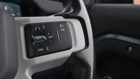 driver using cruise control in a car, pressing integrated buttons on the steering wheel or dashboard to activate and adjust the system for a smoother, more convenient driving experience - Powered by Shutterstock - Get 15% off with code: PIKWIZARD15