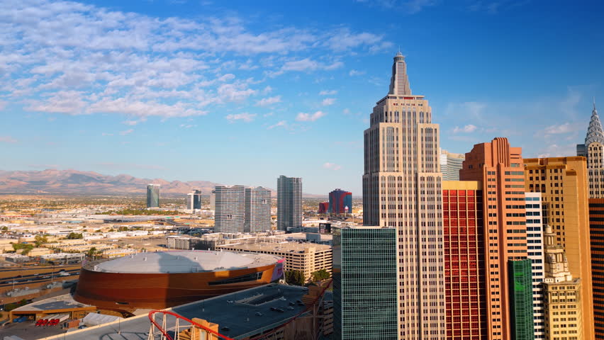 Footage at the tops of the group of buildings of New York-New York Hotel and Casino on the Las Vegas Strip in Paradise, Nevada, United States. Sunlit cityscape and mountains at backdrop.