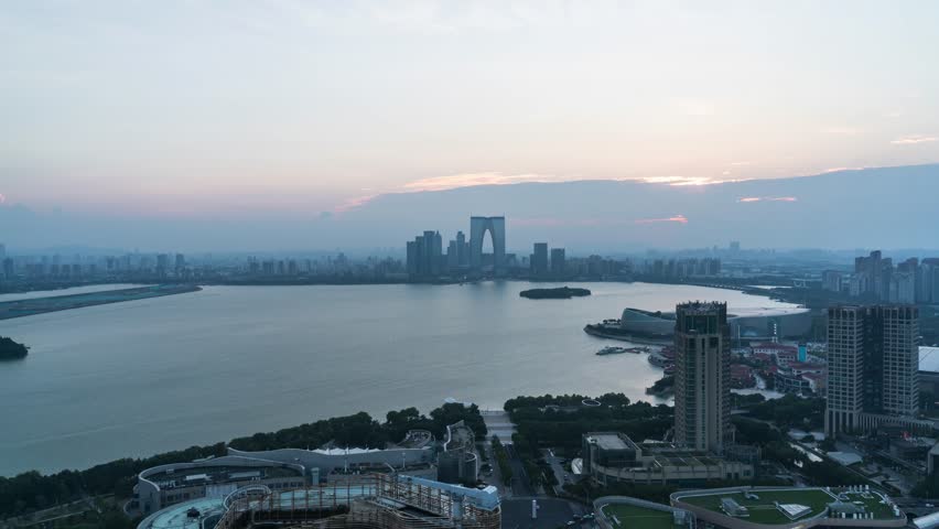 Stunning aerial view of Suzhou Central Business District skyline at sunset with Jinji Lake, featuring modern skyscrapers and urban development in golden hour light.