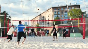 A group of young men are playing beach volleyball in a large city. - Powered by Shutterstock - Get 15% off with code: PIKWIZARD15