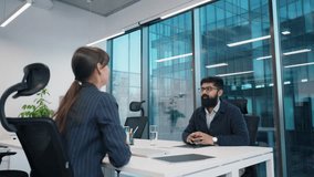 Caucasian HR woman discussing work during job interview. Man holding portfolio, smiling politely. Bright glass office setting, modern business environment. CV interviewing concept. Applying for work. - Powered by Shutterstock - Get 15% off with code: PIKWIZARD15