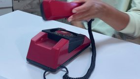 A person dials a vibrant red vintage rotary phone on a white surface, holding the receiver. The image evokes a sense of nostalgia for classic communication. - Powered by Shutterstock - Get 15% off with code: PIKWIZARD15