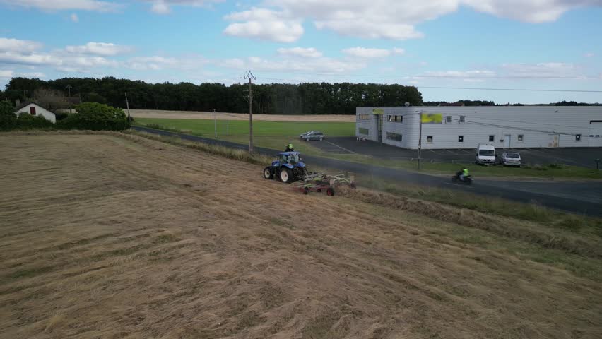 Tractor harvesting grass and making hay bales in field, aerial drone view. Aerial drone footage of a tractor working in an agricultural field during summer. The machine harvests grass and packs it 