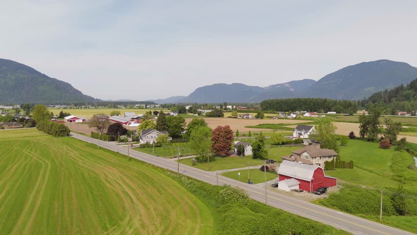 Aerial View of a Peaceful Rural Valley with Farms and Mountains in British Columbia, Canada