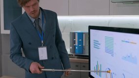 Young businessman presenting analytical charts on large monitor using a metal pointer. Office setting, close-up on financial graphs and corporate data visualization. Professional presentation concept. - Powered by Shutterstock - Get 15% off with code: PIKWIZARD15