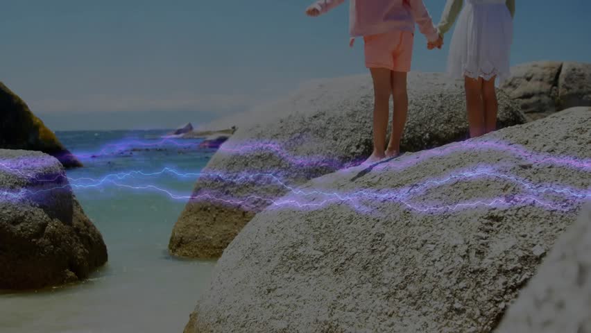 Siblings standing on rock by sea, violet wave drifting causing arm lift greeting sun in media. Adventure, childhood, exploration, beach, serenity, harmony, natural