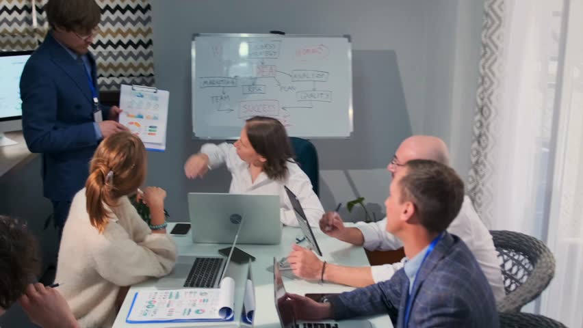 Group of office employees engaged in a business strategy meeting, with a manager presenting analytics charts on a tablet. Colleagues watch, take notes, and discuss project details. - Powered by Shutterstock - Get 15% off with code: PIKWIZARD15