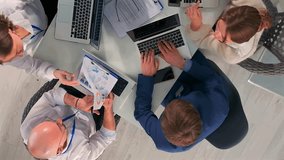 Top-down view of a diverse group of professionals gathered around desk, examining printed charts and documents during team meeting. Laptops, infographics, and business, collaborative work environment. - Powered by Shutterstock - Get 15% off with code: PIKWIZARD15