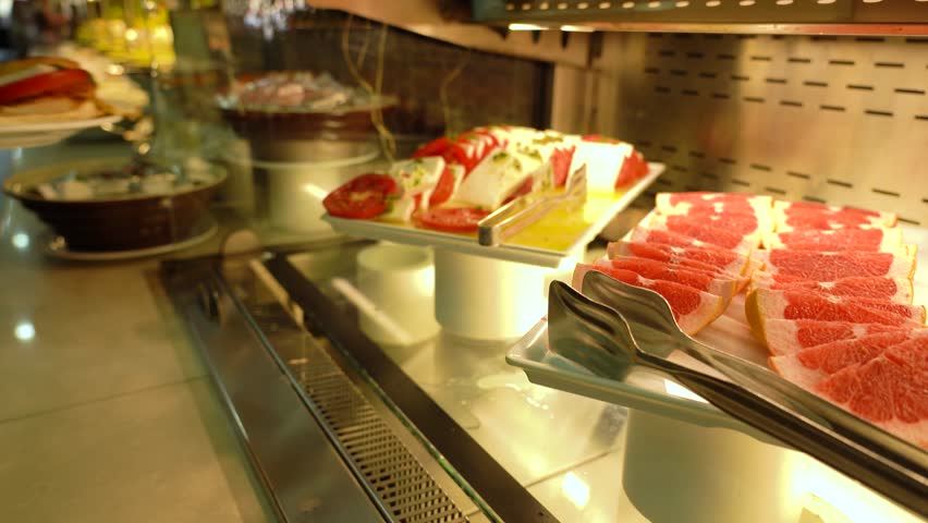 A Tempting Display of Assorted Gourmet Delicacies Featuring Vibrant Fruits and Delectable Pastries in a Well-Lit Restaurant Showcase.