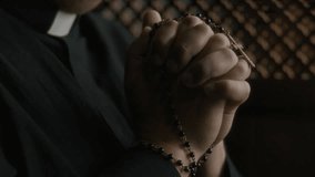 Close-up view of hands of Catholic priest holding rosary beads in solemn prayer inside confessional booth - Powered by Shutterstock - Get 15% off with code: PIKWIZARD15