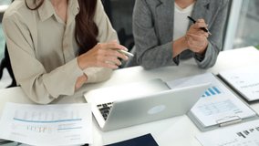 Two Asian adult women professionals analyze financial data charts on a laptop in a bright office environment They discuss important business reports - Powered by Shutterstock - Get 15% off with code: PIKWIZARD15