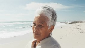 Senior woman gazing off-camera, generating floating emoji icons on beach for social media marketing. Serenity, reflection, digital, relaxation, contemplative, seaside, cheerful - Powered by Shutterstock - Get 15% off with code: PIKWIZARD15