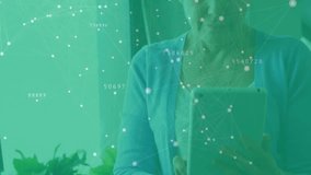 Senior woman lifting tablet at home and tapping screen while exploring technology network overlay. Technology, connectivity, senior, digital, innovation, lifestyle, modern - Powered by Shutterstock - Get 15% off with code: PIKWIZARD15