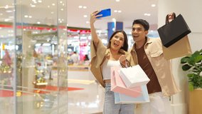 Happy Asian family couple using mobile phone taking selfie together while shopping at department store on holiday vacation. People enjoy urban lifestyle shopping, buying and spending at shopping mall. - Powered by Shutterstock - Get 15% off with code: PIKWIZARD15