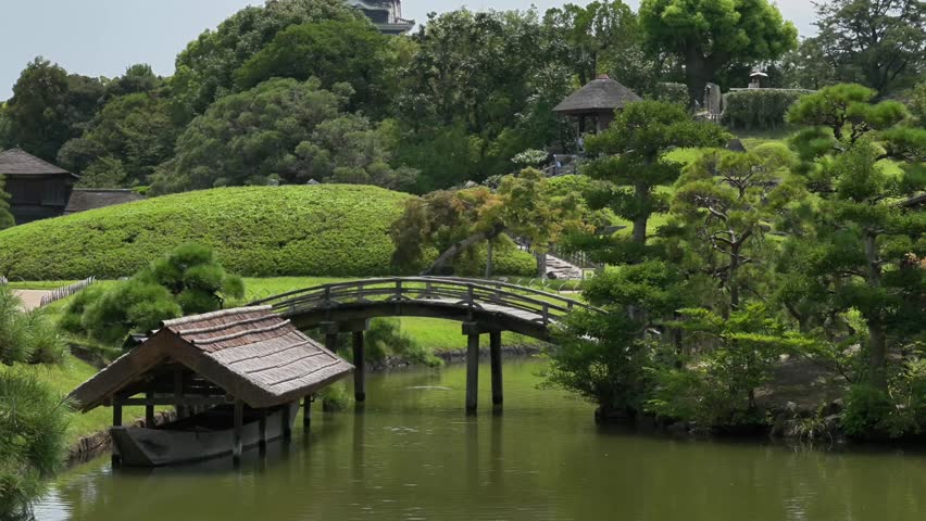 Wooden bridge, boat, house and pavilion on the island in Okayama Korakuen