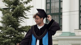 Modern graduate boy with cap on his head and graduation gown poses and takes selfies on his phone to send to his parents and friends. Pictures from the graduation ceremony for graduating students - Powered by Shutterstock - Get 15% off with code: PIKWIZARD15