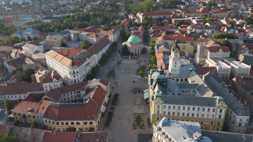 Descending over Széchenyi Square in Pécs, approaching the Mosque of Pasha Qasim and historic city center.