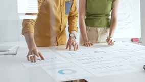 Professional team collaborating, reviewing financial documents and graphs on laptop with printed data spread across conference table in contemporary workspace. Business people concept - Powered by Shutterstock - Get 15% off with code: PIKWIZARD15