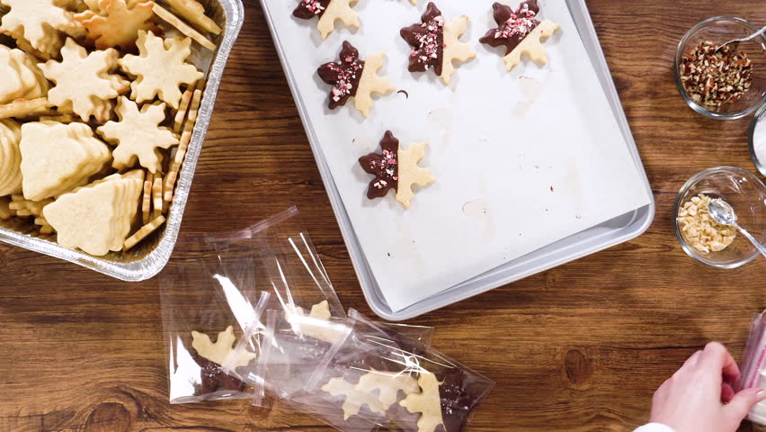Flat lay. Carefully packaging Christmas cutout cookies, half-dipped in chocolate and presented in clear cellophane wrapping, perfect for festive gifting.