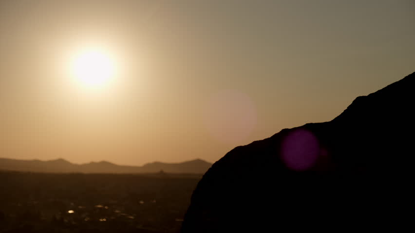 Silhouette of man hiker extending helping hand to friend while climbing mountain