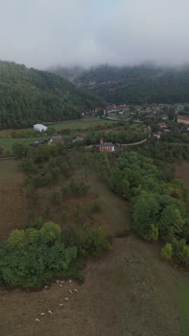Aerial view of small city surrounded with misty mountains