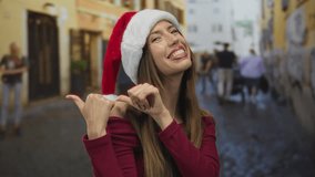Woman pointing thumbs at herself on a narrow cobblestone street wearing a red santa hat and off shoulder top; joy. - Powered by Shutterstock - Get 15% off with code: PIKWIZARD15