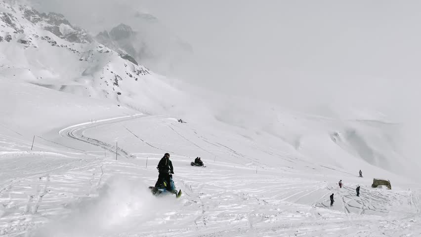 Snowmobile ascending ski slopes with skiers and fresh tracks on Tetnuldi mountain, Svaneti region, Georgia, winter travel and adventure concept