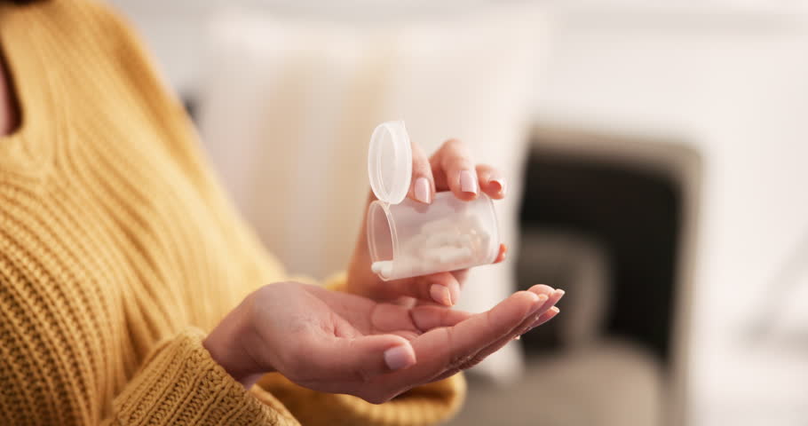 Hands, woman and container with pills at house for supplements, iron medication and prescription. Female person, tablets and drinking water for illness, pharmaceutical recovery and chronic treatment