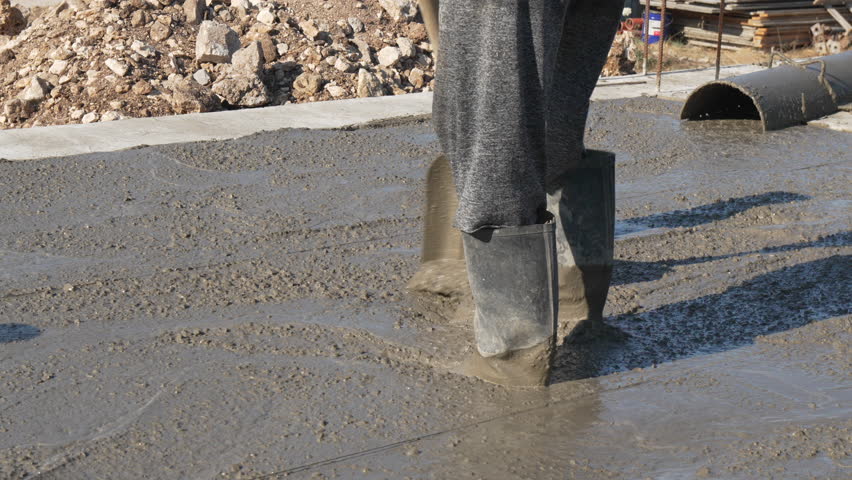 Concrete construction worker spreading wet floor on building site
