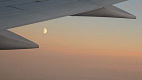 Stunning sunset view from airplane window with clouds, moon in the sky and aircraft wing silhouette – breathtaking aerial travel scene above the clouds - Powered by Shutterstock - Get 15% off with code: PIKWIZARD15