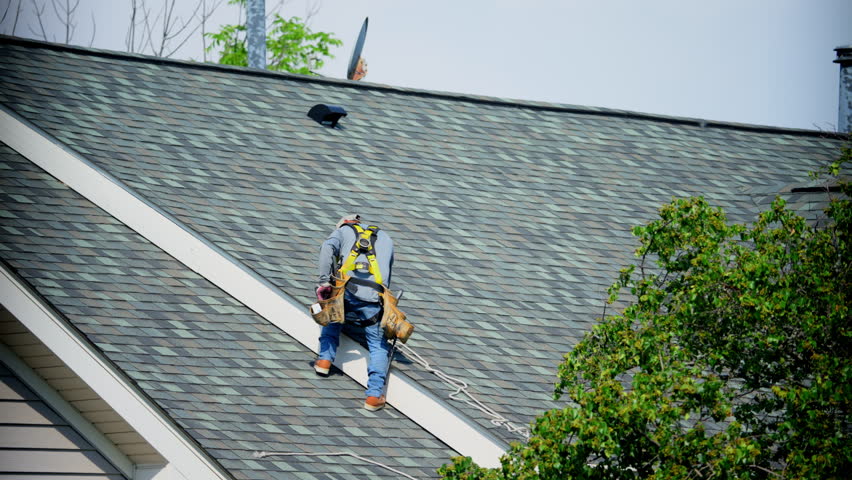 Roofers finishing roof repair putting the shingles in right order and nailing them on the house roof. Element of roof renovation