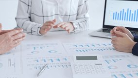 Business professionals discussing financial reports and data analysis during an office meeting, reviewing market trends and performance charts on paper and laptop - Powered by Shutterstock - Get 15% off with code: PIKWIZARD15