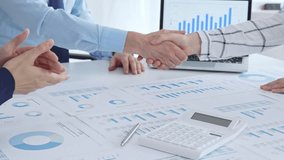 Business people shaking hands over financial documents and charts, confirming a successful agreement and partnership during a corporate meeting in the office - Powered by Shutterstock - Get 15% off with code: PIKWIZARD15