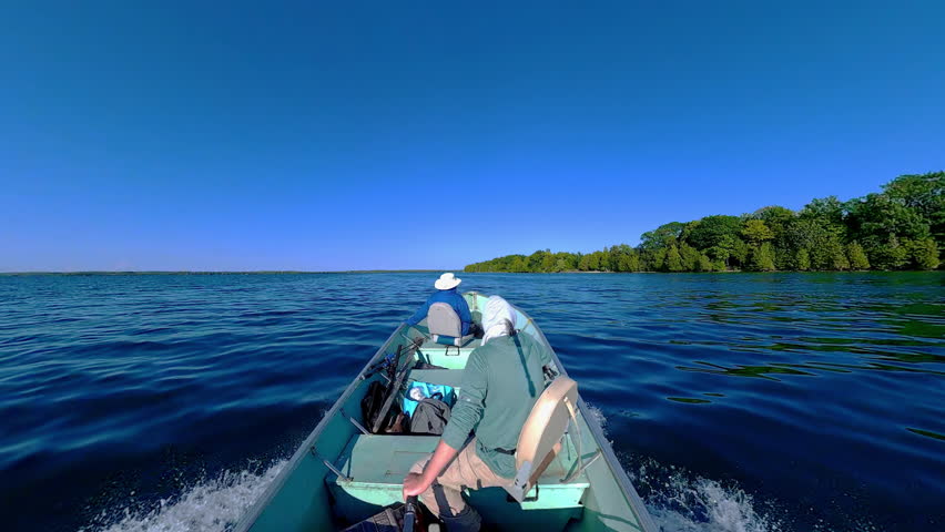 Man driving bass boat while woman seating at the front. Power sport, outboard fishing boat, with two people. Man and woman boating during fishing on the small v-hull boat.