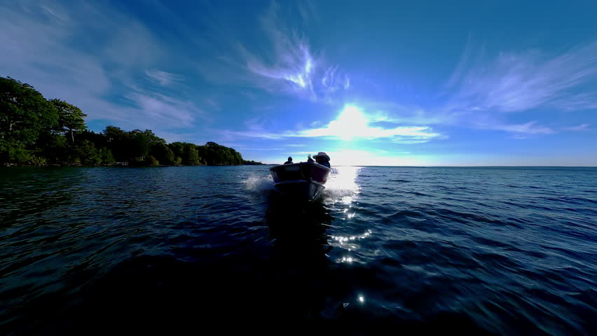Man driving bass boat while woman seating at the front. Power sport, outboard fishing boat, with two people. Man and woman boating during fishing on the small v-hull boat.