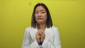 Woman in white jacket looks nervous against a vibrant yellow background, highlighting expressions of uncertainty and hesitance in an isolated studio setting. - Powered by Shutterstock - Get 15% off with code: PIKWIZARD15