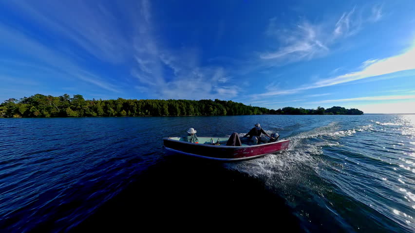 Man driving bass boat while woman seating at the front. Power sport, outboard fishing boat, with two people. Man and woman boating during fishing on the small v-hull boat.