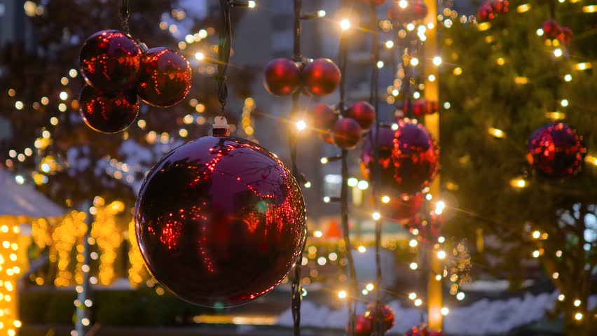 Close up view: red Christmas ornaments with warm glowing lights in Belgrade in evening - blurred background. Festive holiday atmosphere, New Year and seasonal decorations.