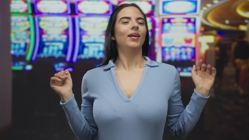 Woman smiling indoors at a vibrant casino with neon slot machines in the background, showing joyful expression and celebration, capturing excitement and luck in a lively gaming atmosphere.