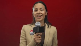 Woman reporter holding microphone with i voted badge standing against red wall smiling confidently with united states flag pin on lapel jacket - Powered by Shutterstock - Get 15% off with code: PIKWIZARD15
