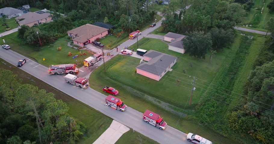 Firefighter trucks at fire alarm scene of suburban house. First responders at potential fire hazard at Florida home.