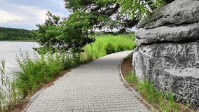 A beautifully serene lakeside walkway that is framed by lush greenery and rugged rocky edges, perfect for nature - Powered by Shutterstock - Get 15% off with code: PIKWIZARD15