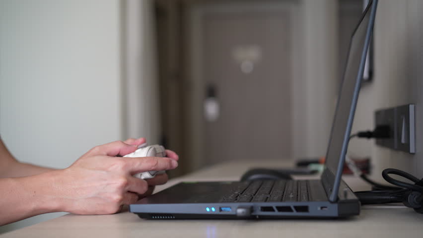Closeup people hand or gamer holding joystick or gaming controller to enjoy playing game on computer notebook or laptop console by joy stick in living room for entertrainment relax on holiday