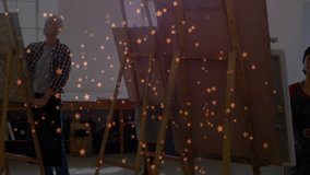 Mature male adjusting easel and peers painting canvases in studio class while star overlay floating. Art, creativity, collaboration, learning, inspiration, mentorship, abstract - Powered by Shutterstock - Get 15% off with code: PIKWIZARD15