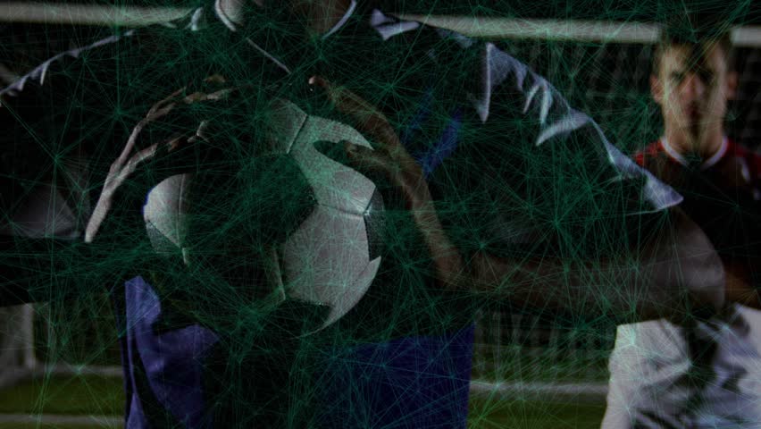 Goalkeeper gripping ball camera pulling back at night revealing teammate boosting tech overlay. Athletic, teamwork, technology, soccer, digital, night, sportsmanship