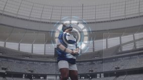 Male rugby player gripping ball and activating HUD in stadium while analyzing data via charts. Athlete, technology, innovation, sports, futurism, data, analysis - Powered by Shutterstock - Get 15% off with code: PIKWIZARD15