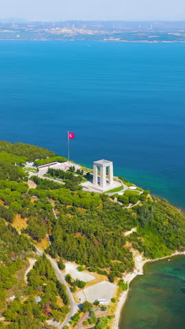 Vertical video. Eceabat, Turkey. Dardanelles Strait, coastline, Canakkale Martyrs Memorial, Turkish flag, Hisarlik Hill, clear day, drone. Aerial View. Rich colors